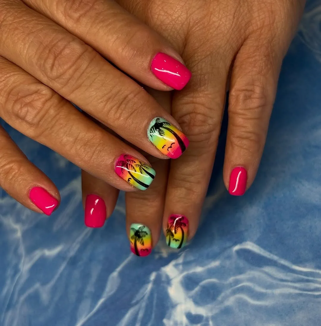 A close-up shot of hands showcasing vibrant palm tree nail art with a gradient sunset background and solid hot pink nails.